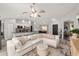 Spacious living room showcases a large sectional sofa, ceiling fan, and open layout to kitchen at 6873 Sw 131St Pl, Ocala, FL 34473