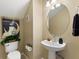 Cozy half bathroom featuring a stylish vanity, round mirror, and decorative poster at 7752 Moser Ave, Windermere, FL 34786