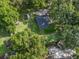 An aerial view of the property showcasing mature trees and green lawn, with several outbuildings nearby at 5434 Se 39Th Ave, Ocala, FL 34480