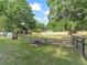 Large backyard featuring a fire pit, green grass, and mature trees providing a serene outdoor setting at 5434 Se 39Th Ave, Ocala, FL 34480