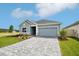 Inviting curb appeal with a light blue home, paver driveway, well-kept lawn, and stone accents under a sunny sky at 6087 Sacred Oak Ave, Mount Dora, FL 32757