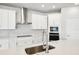 Close-up view of a kitchen featuring a stainless steel sink, white cabinets, and built-in stainless steel microwave and oven at 6087 Sacred Oak Ave, Mount Dora, FL 32757