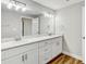 Bathroom featuring white cabinets, double sinks, large mirrors, and wood-look flooring at 701 N Vermont Ave, Lakeland, FL 33801