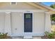 Close up view of a charming home featuring a dark blue front door, textured siding and decorative plants at 701 N Vermont Ave, Lakeland, FL 33801