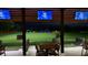 Nighttime view of Toptracer Range with multiple hitting bays, TVs, and a golf course backdrop at 1142 Mariner Cay Dr, Haines City, FL 33844