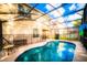 Backyard oasis featuring a sparkling pool, screened enclosure, and a view of the home's rear facade at 1142 Mariner Cay Dr, Haines City, FL 33844