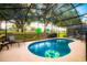 Secluded backyard with a sparkling pool, screened-in enclosure, and views of the surrounding nature at 1142 Mariner Cay Dr, Haines City, FL 33844