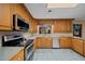Bright kitchen with oak cabinets, tile backsplash, and stainless steel appliances under a skylight at 7795 Sw 72Nd Ct, Ocala, FL 34476