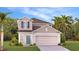 Charming two-story home featuring a two-car garage, inviting entryway, and landscaped front yard at 5657 Portico Pl, Kissimmee, FL 34758