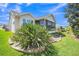 The backyard has well-manicured landscaping and plants, as well as a screened-in patio and the exterior of other homes at 1709 Latta Ct, The Villages, FL 32162