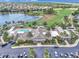 Aerial view of community clubhouse with a pool, mature landscaping, parking, lake, and golf course at 1709 Latta Ct, The Villages, FL 32162