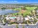 Aerial view of community clubhouse with a pool, mature landscaping, ample parking, and golf course at 1709 Latta Ct, The Villages, FL 32162