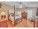 Spacious main bedroom with a four-poster bed, wooden furniture, and neutral color scheme at 1709 Latta Ct, The Villages, FL 32162