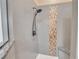 Modern shower with gray tiled walls, decorative mosaic tile, and a rainfall shower head at 1709 Latta Ct, The Villages, FL 32162
