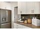 Kitchen with stainless steel appliances, gray countertops, white cabinets, and dark tiled backsplash at 1899 Clear Sky Dr, Kissimmee, FL 34744