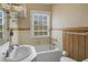 Cozy bathroom featuring a tub, sink, wood paneling and a bright, well-lit window at 2417 Coventry Ave, Lakeland, FL 33803