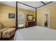 Traditional bedroom with a four poster bed, ornate armchair, and a bright arched window at 2417 Coventry Ave, Lakeland, FL 33803