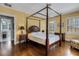 Well-lit bedroom features a four poster bed, hardwood floors and a view to the bathroom at 2417 Coventry Ave, Lakeland, FL 33803