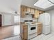 Galley kitchen with wood cabinets and white appliances is open to the adjacent living area at 9526 Turkey Oak Bnd, Orlando, FL 32817