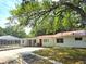 Home exterior featuring white siding, a red door, and lush trees at 5045 Swindell Rd, Lakeland, FL 33810