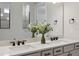 Bathroom boasts a double vanity with modern fixtures, a large mirror, and decorative floral arrangements at 2797 Top Hill Ct, Minneola, FL 34715