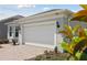 Close-up of a two-car garage door framed by lush greenery and a brick paver driveway at 2797 Top Hill Ct, Minneola, FL 34715