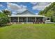 Exterior view showing a spacious screened-in porch stretching along the back, opening to a manicured lawn at 1395 S Lake Reedy Blvd, Frostproof, FL 33843