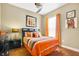 Comfortable bedroom features a ceiling fan, hardwood floors, neutral walls, window with orange curtains, and colorful artwork at 2161 Longleaf Cir, Lakeland, FL 33810