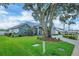 Charming single-story home featuring a lush green lawn, mature tree, manicured garden beds, and a circular driveway at 2161 Longleaf Cir, Lakeland, FL 33810