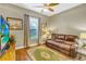 Cozy living room with a leather sofa, green patterned rug, hardwood floors, window with blinds and curtains, and a TV at 2161 Longleaf Cir, Lakeland, FL 33810