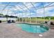 Screened-in pool with waterfall feature, surrounding patio, and a picturesque view of the green space beyond at 2161 Longleaf Cir, Lakeland, FL 33810