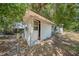 Exterior view of a small, white shed in the backyard with a partially opened door at 129 5Th Jpv St, Winter Haven, FL 33880