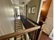 Upper hallway with wooden railing overlooking staircase and view of bathroom at 1056 Castle Pines Ct, Reunion, FL 34747