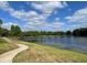 Community pond with manicured grass, mature trees, and lighted sidewalk, with views of the pond at 313 Morning Creek Cir, Apopka, FL 32712