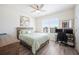Well-lit bedroom with a queen bed, dual monitors, and a light green patterned comforter, offering a cozy retreat at 5616 Siltstone St, Lakeland, FL 33811