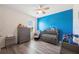 Comfortable Bedroom featuring a gray crib, dresser, and a glider chair with a bright blue accent wall at 5616 Siltstone St, Lakeland, FL 33811