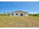 Backyard of modern home featuring a covered patio with large windows and a spacious lawn under a clear sky at 2021 Valencia Dr, Indian Lake Estates, FL 33855
