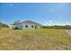 Backyard of modern home featuring a covered patio with large windows and a spacious lawn under a clear sky at 2021 Valencia Dr, Indian Lake Estates, FL 33855