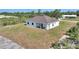 An exterior elevation view of a white home with a light-colored roof and a spacious lawn at 2021 Valencia Dr, Indian Lake Estates, FL 33855