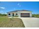 Charming single-story home featuring a two-car garage, neutral stucco, and a well-manicured lawn at 2021 Valencia Dr, Indian Lake Estates, FL 33855