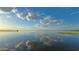 Scenic lake view with a wooden pier extending into calm waters, reflecting a blue, cloudy sky at 2021 Valencia Dr, Indian Lake Estates, FL 33855