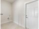 Clean laundry room with crisp white wall paint, a white door and gray flooring at 2021 Valencia Dr, Indian Lake Estates, FL 33855