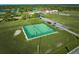 Aerial view of a green tennis court on a grassy field with players and the clubhouse in the background at 2021 Valencia Dr, Indian Lake Estates, FL 33855