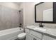 Bathroom featuring tile surround, tub, and granite countertop with black hardware at 7688 Somersworth Dr, Kissimmee, FL 34747