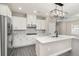 Modern kitchen featuring an island, stainless steel appliances, white cabinetry, and a stylish lighting fixture at 7688 Somersworth Dr, Kissimmee, FL 34747
