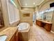 Spacious bathroom featuring a jetted tub, granite countertops, and separate vanity areas at 2660 Wyndsor Oaks Way, Winter Haven, FL 33884
