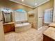 Bright bathroom with large tub, arched window, granite counters, and tile surround at 2660 Wyndsor Oaks Way, Winter Haven, FL 33884