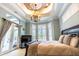 Bright main bedroom with French doors, bay windows, and decorative tray ceiling with a chandelier at 2660 Wyndsor Oaks Way, Winter Haven, FL 33884