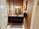 Intimate powder room with granite countertop, decorative mirror, and sconce lighting at 2660 Wyndsor Oaks Way, Winter Haven, FL 33884
