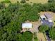 Aerial view of a home with a metal roof nestled among the trees and near an open field at 6702 Brookridge Trl, Lakeland, FL 33810